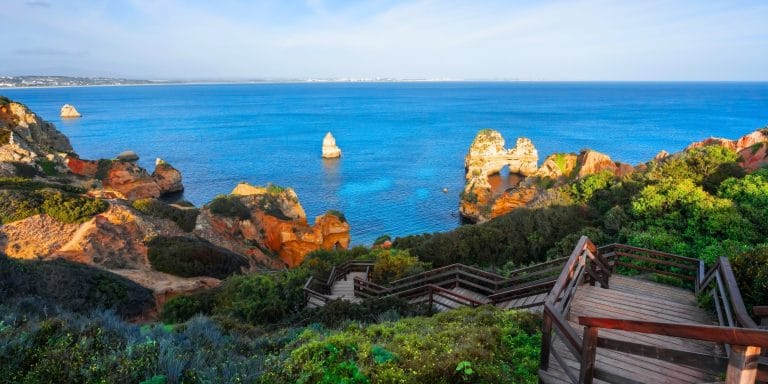 Escaleras de acceso a Praia do Camilo con vistas a los acantilados y aguas turquesas en el Algarve, Portugal