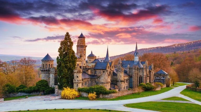 Castillo de Löwenburg en Kassel Hesse Alemania al atardecer con cielo de nubes y montañas de fondo