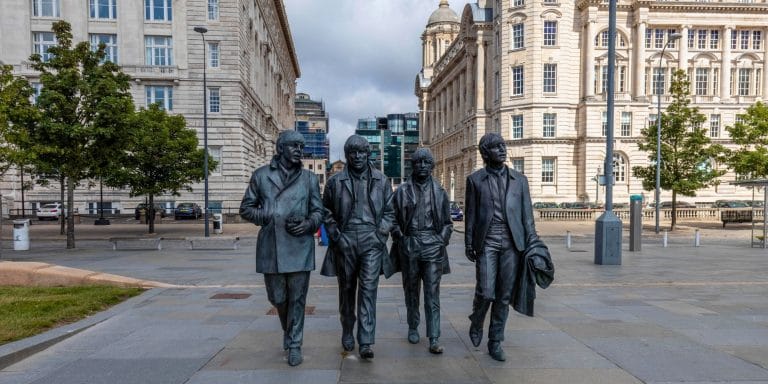Escultura de The Beatles en Liverpool Inglaterra con edificios históricos de fondo