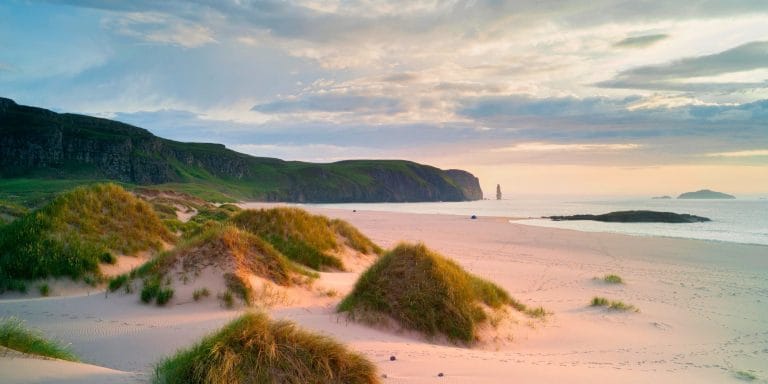 Playa de Sandwood Bay en Escocia con dunas de arena y acantilados al fondo