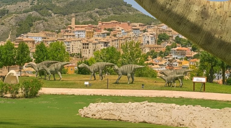 Figuras de dinosaurios en el parque paleontológico de Cuenca con la ciudad al fondo