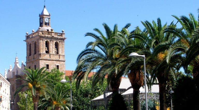 Torre de la Iglesia de la Asunción en Villanueva de la Serena Badajoz rodeada de palmeras en la Plaza de España