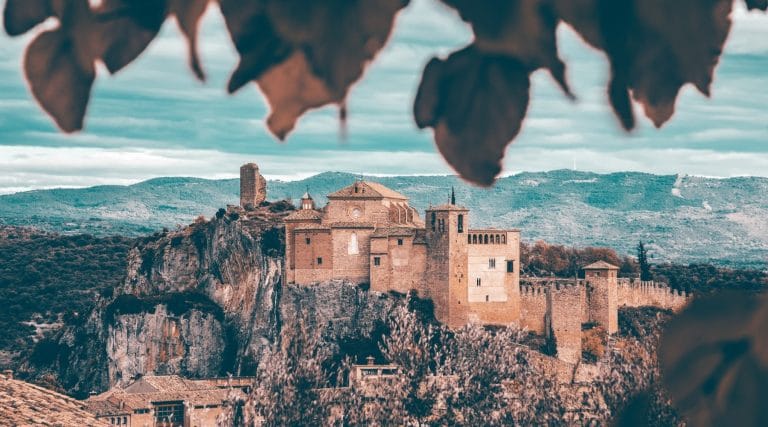 Castillo y colegiata de Alquézar en Huesca vistos desde un mirador con hojas en primer plano