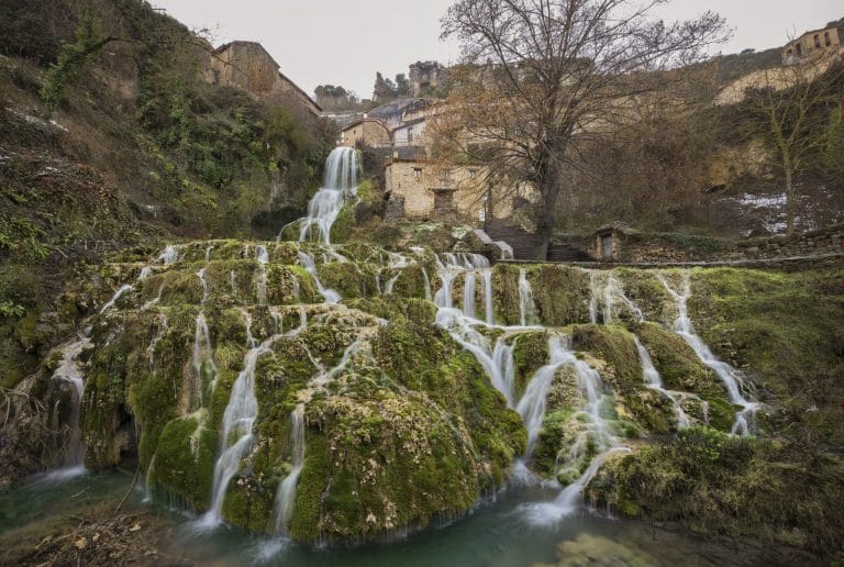Cascada en el pueblo de Orbaneja del Castillo, Burgos, España, rodeada de casas tradicionales y naturaleza