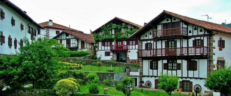 vista del pintoresco pueblo de etxalar en navarra, rodeado de naturaleza, bosques frondosos y caserios tradicionales, ideal para paseos y turismo rural.