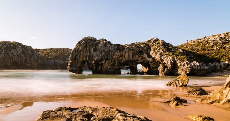 Playa de Cuevas del Mar en Llanes, Asturias, con formaciones rocosas únicas y aguas cristalinas.