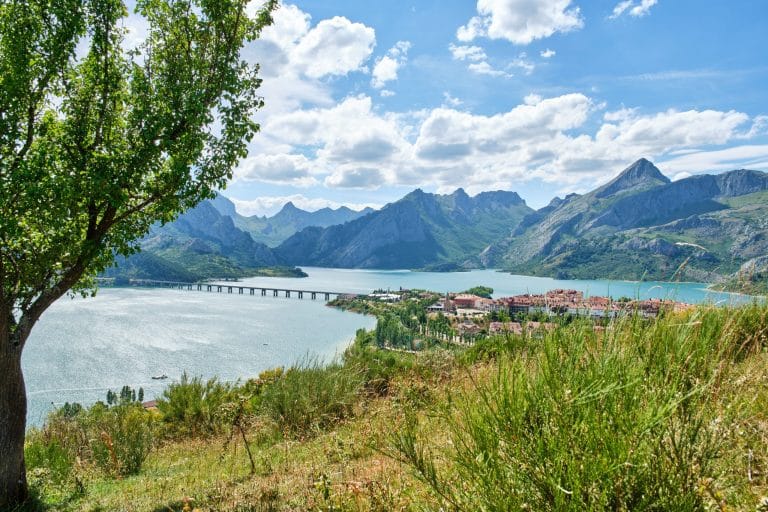 Pueblo de Riaño en León, España, con lago y montañas al fondo en un día soleado