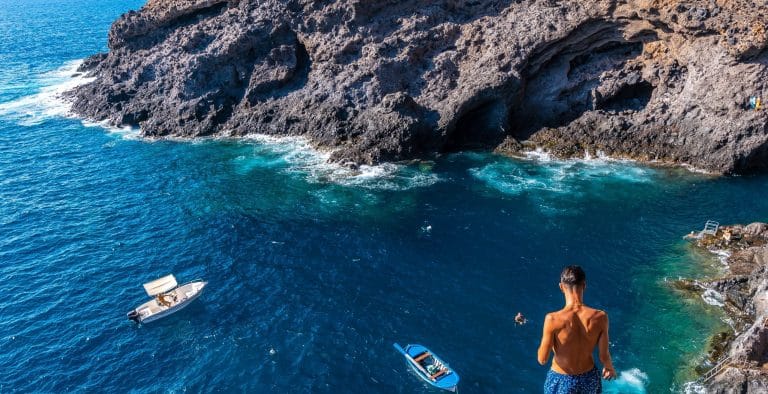 Un joven realiza un espectacular salto desde gran altura hacia el agua cristalina en el pintoresco pueblo costero de Porís de Candelaria, en la isla de La Palma, Islas Canarias