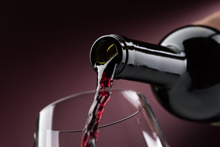 Primer plano de vino tinto siendo vertido en una copa, resaltando su color intenso y su textura sedosa.