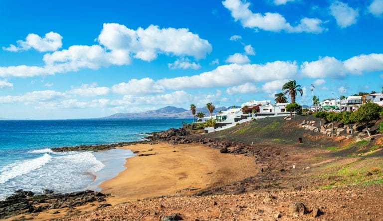 Playa El Barranquillo en Puerto de Lanzarote, con arena dorada y aguas cristalinas.