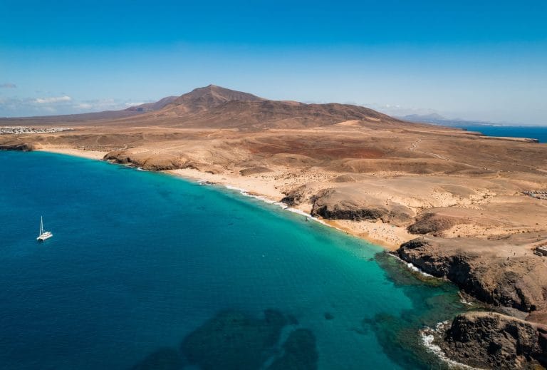 Vista aérea de las playas de Papagayo en Lanzarote, con aguas turquesas y arena dorada en la costa volcánica.