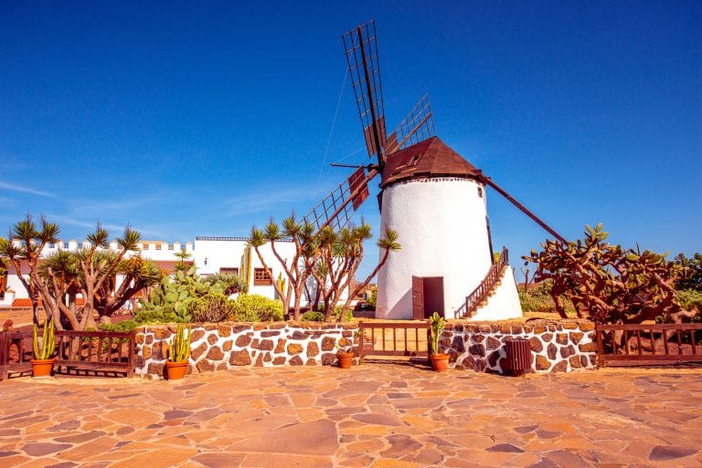 Molino de viento tradicional en Fuerteventura, rodeado de paisaje árido y montañoso
