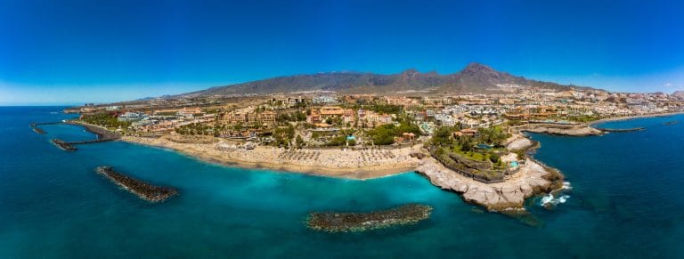laya y costa de El Duque en Costa Adeje, Tenerife, con aguas cristalinas y arena dorada.