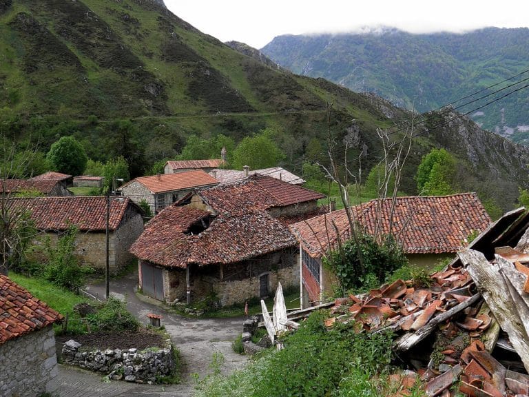 Casas de piedra con tejados de teja roja en la aldea de San Román, Amieva, rodeada de montañas en el oriente de Asturias