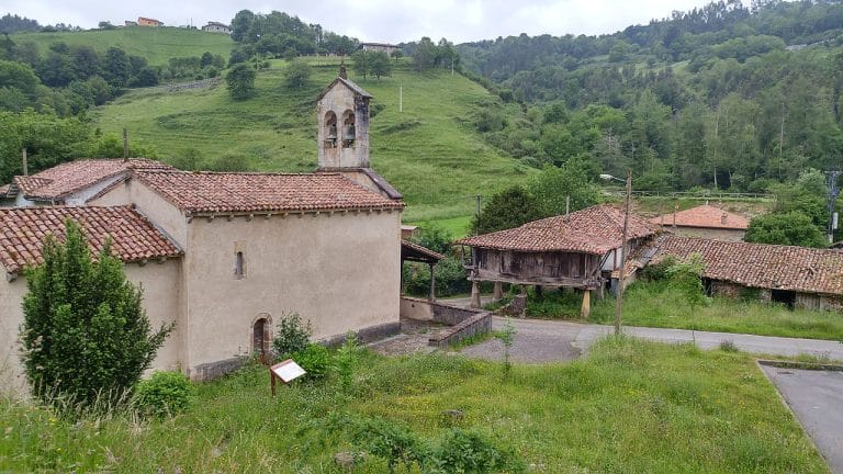 Iglesia de San Julián de Viñón en Cabranes, Asturias, junto a hórreo tradicional en un entorno rural con colinas verdes