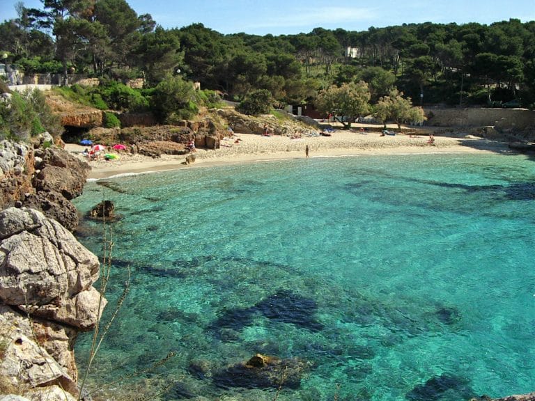 Vista de Cala Gat en Mallorca con aguas cristalinas y arena blanca en un entorno paradisíaco