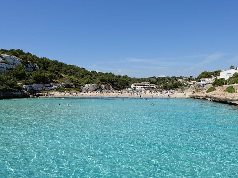 Vista de Cala Romántica en Mallorca con aguas cristalinas y arena dorada rodeada de acantilados