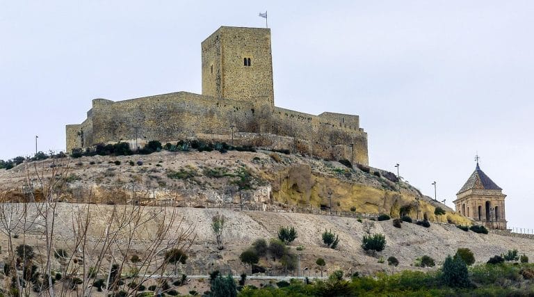 Vista del castillo de Alcaudete en Jaén sobre un cerro con murallas de piedra medievales.