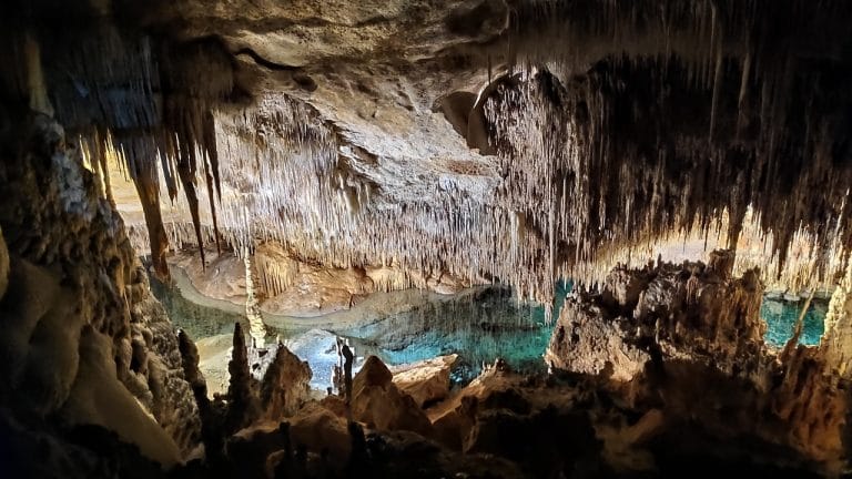 Interior de las Cuevas del Drach en Mallorca con formaciones de estalactitas y un lago subterráneo iluminado