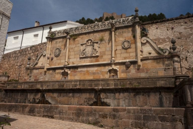 Fuente renacentista de piedra con relieves heráldicos y caños en el casco histórico de Segura de la Sierra