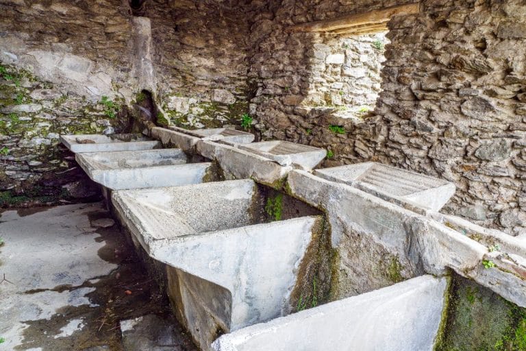 interior de un antiguo lavadero público de piedra en capileira, con varias pilas de lavado y muros de piedra rústica.