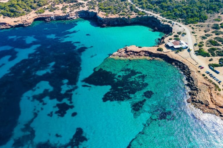 Vista aérea de la cala Comte con aguas turquesas y acantilado rocoso.