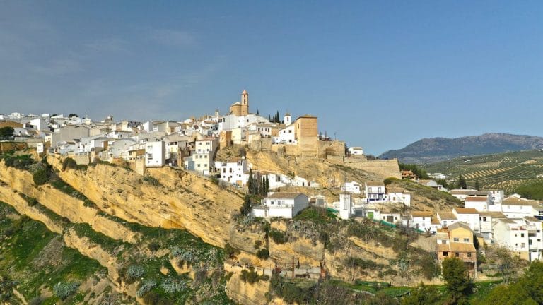 Vista panorámica de los pueblos blancos de Iznájar en Córdoba, con casas sobre un acantilado y paisaje de olivares.
