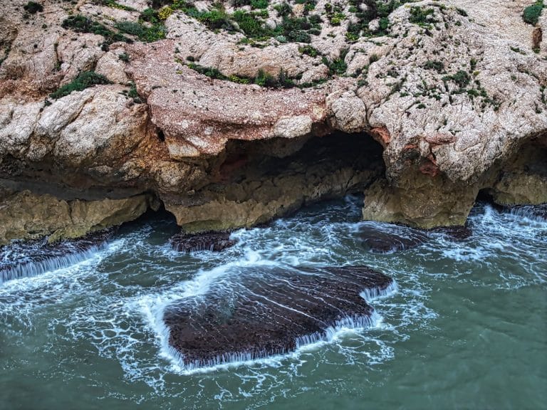 Formaciones rocosas en la costa con olas del mar en el Rincón de la Victoria, Málaga