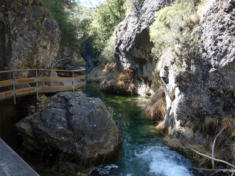 Pasarela de madera junto al río Borosa rodeada de paredes rocosas y agua cristalina en la sierra de Cazorla