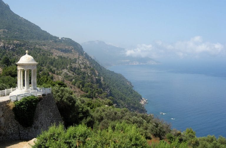 pequeño templete blanco con columnas jónicas en un mirador sobre el acantilado y vistas al mar mediterráneo en son marroig, mallorca.