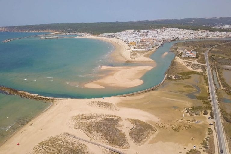 Vista aérea del río Barbate desembocando en una playa de arena dorada junto al pueblo de Barbate.