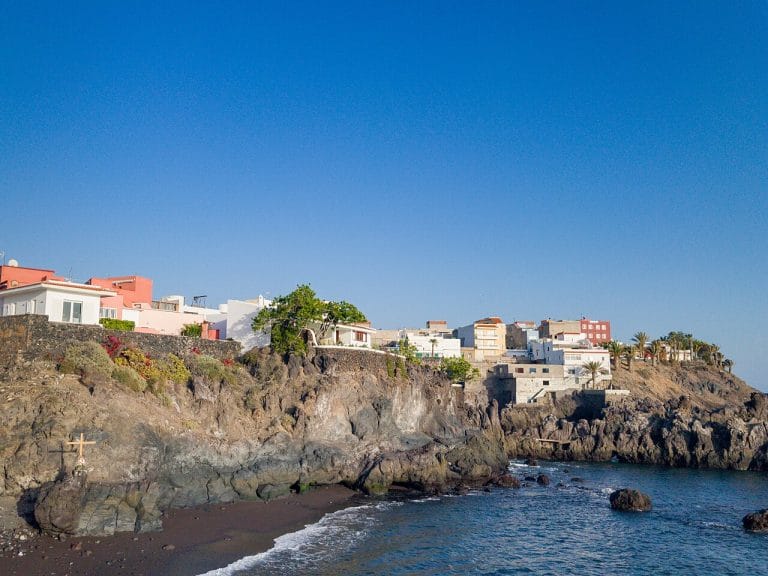 Vista del pueblo costero de Alcalá en Tenerife con casas de colores sobre los acantilados volcánicos junto al mar Atlántico bajo un cielo despejado