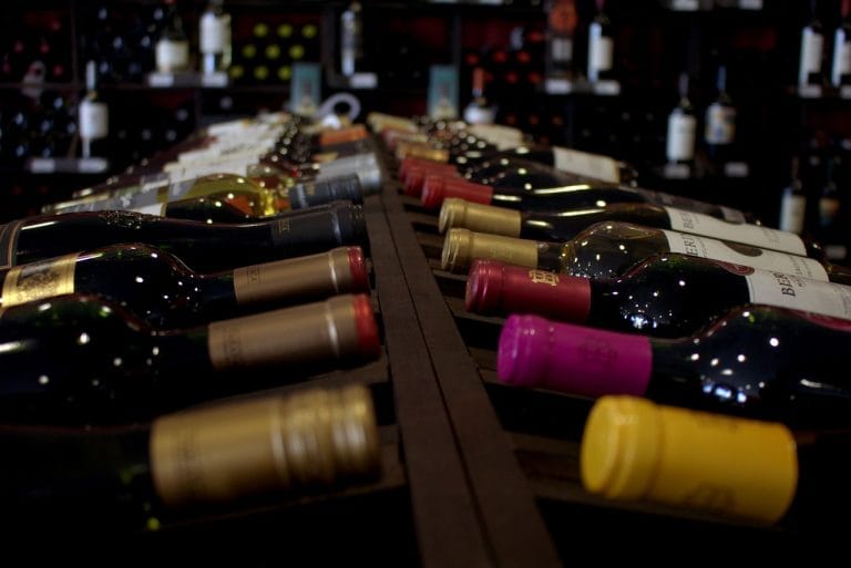 Botellas de vino alineadas en una bodega tradicional en Bullas con variedad de colores en los tapones