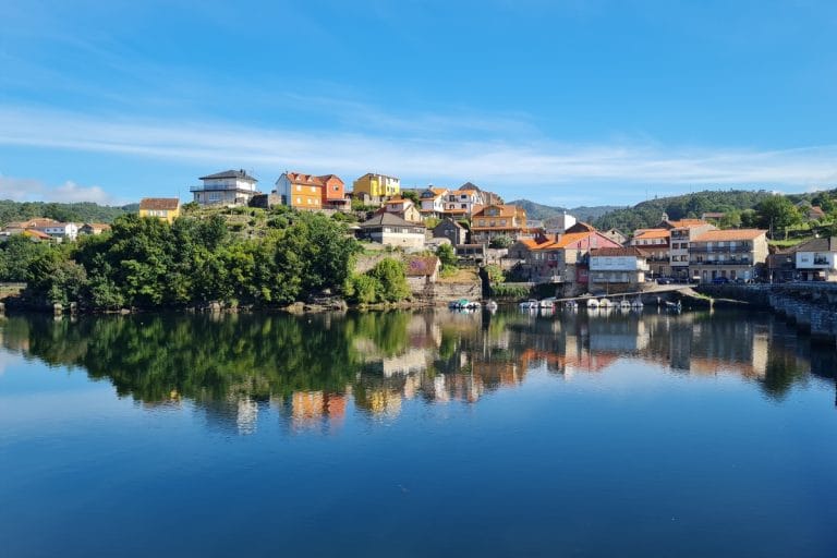 Vista de las casas de Caldas de Reis reflejadas en el río, rodeadas de naturaleza en un entorno de la Reserva de la Biosfera.