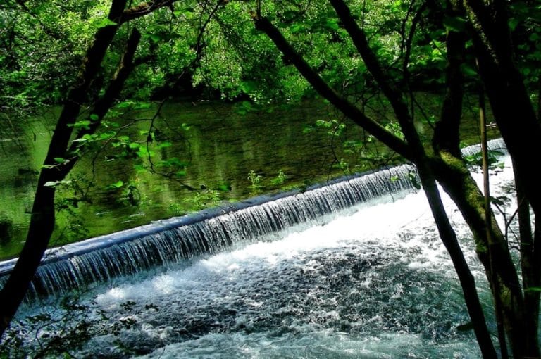 Pequeña cascada en el río rodeada de árboles en As Pontes de García Rodríguez, Galicia