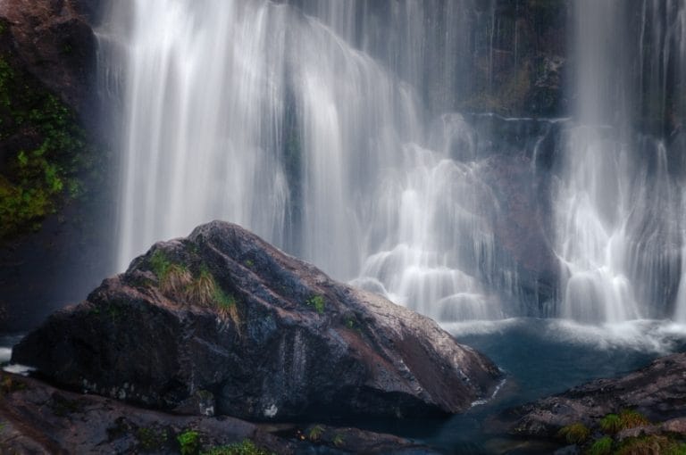 Cascada de Belelle en Fene, Galicia, con el agua cayendo sobre una gran roca en un entorno natural