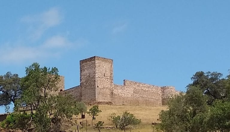Vista del Castillo de El Real de la Jara, fortaleza medieval entre encinas en la Sierra Morena de Sevilla