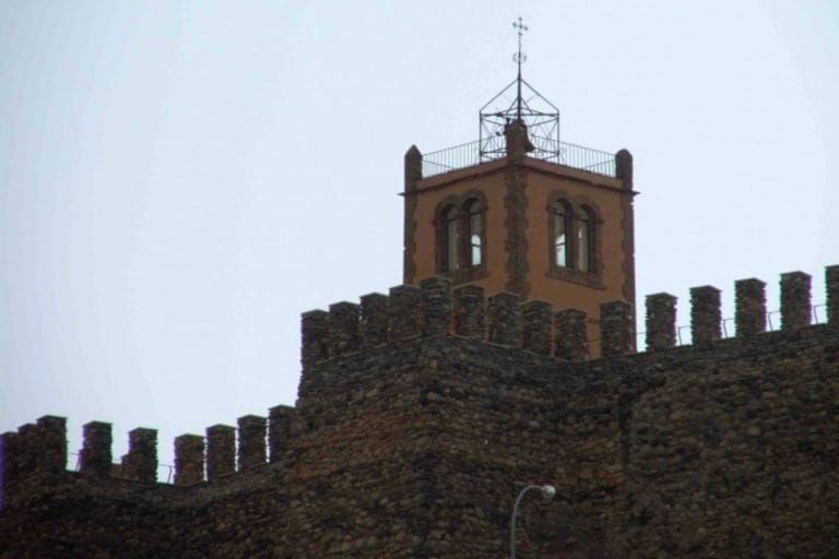 Torre almenada del castillo de Serón alzándose sobre las murallas de mampostería, con el campanario y su disposición de almenas contra un cielo despejado.