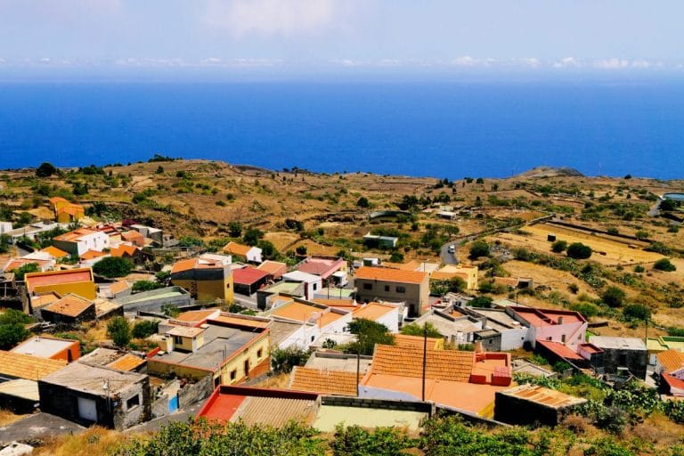 Vista panorámica del pueblo de El Pinar en El Hierro, con casas de colores sobre un paisaje árido y el océano Atlántico al fondo.