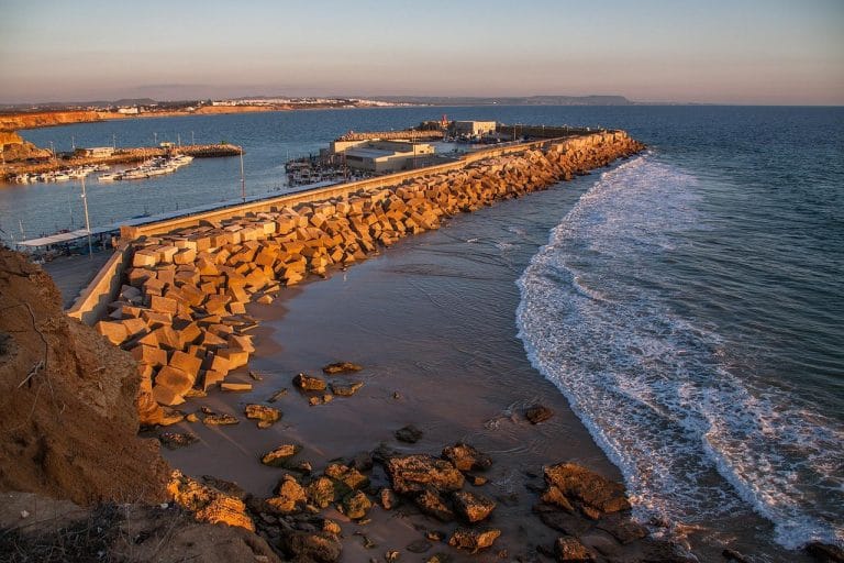 Muelle y rompeolas en Conil de la Frontera con barcos amarrados y costa rocosa
