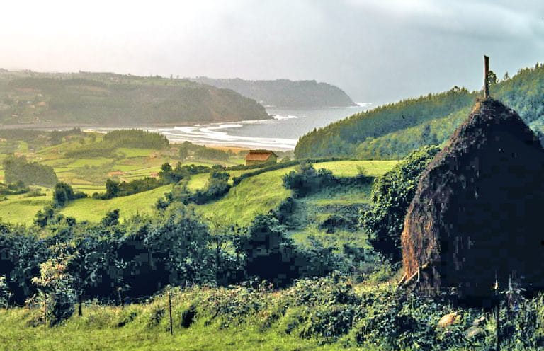 Vista panorámica de la costa asturiana con paisaje rural, prados verdes y el mar al fondo