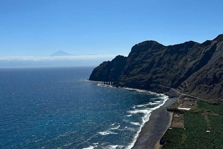 Vista de la playa de Hermigua en La Gomera, con los antiguos pescantes y el Teide al fondo entre las nubes