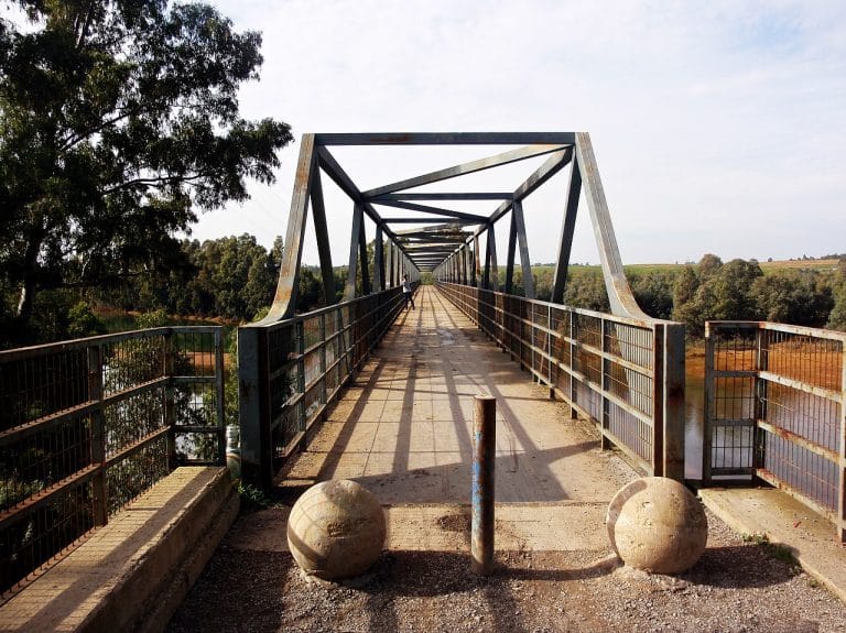 Pasarela peatonal sobre el antiguo puente del ferrocarril en Gibraleón, rodeado de paisaje natural y vegetación