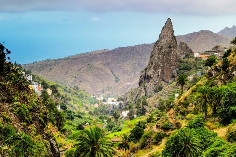 Vista del Roque de San Pedro rodeado de vegetación y casas rurales en Hermigua, La Gomera