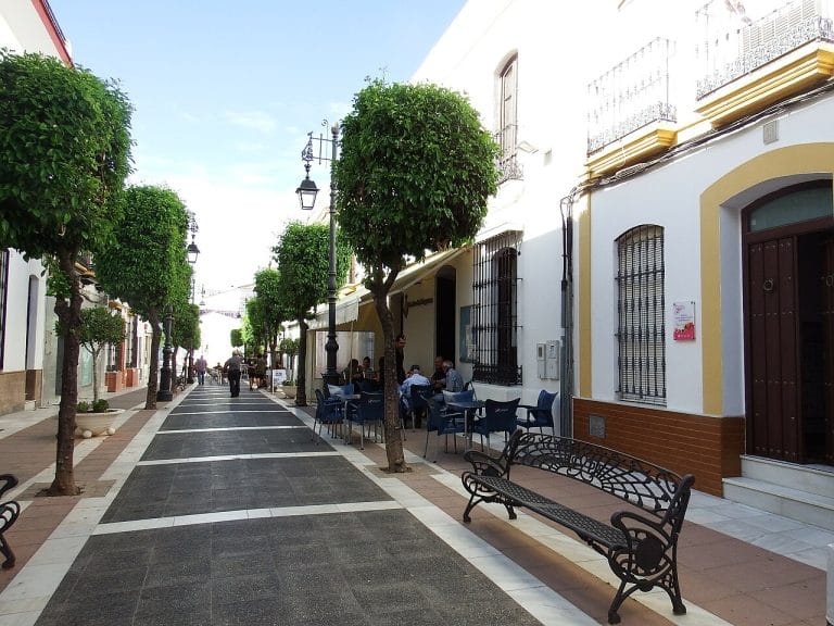 Vista de una calle peatonal con terrazas y árboles en San Juan del Puerto, Huelva