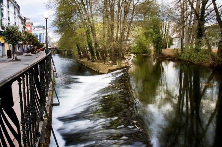 Paseo junto al río Sarria a su paso por el centro urbano, con árboles y pasarela peatonal en la localidad de Sarria, Lugo, Galicia
