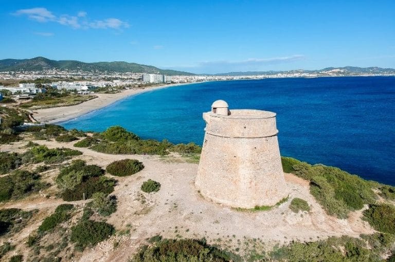 Vista aérea de la Torre del Carregador en Ibiza con la Playa d’en Bossa al fondo y el mar Mediterráneo en primer plano