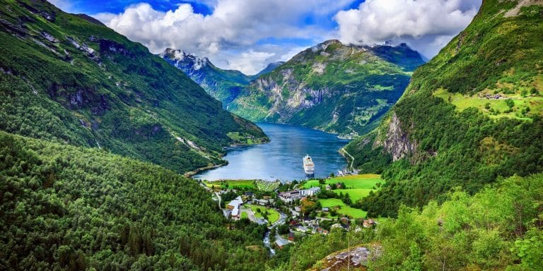 Vista panorámica del fiordo de Geiranger en Noruega con montañas verdes y un crucero en el agua