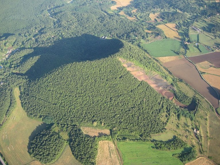 Vista aérea del volcán Croscat, con su característico corte lateral visible entre los campos verdes del Parque Natural de la Zona Volcánica de la Garrotxa.