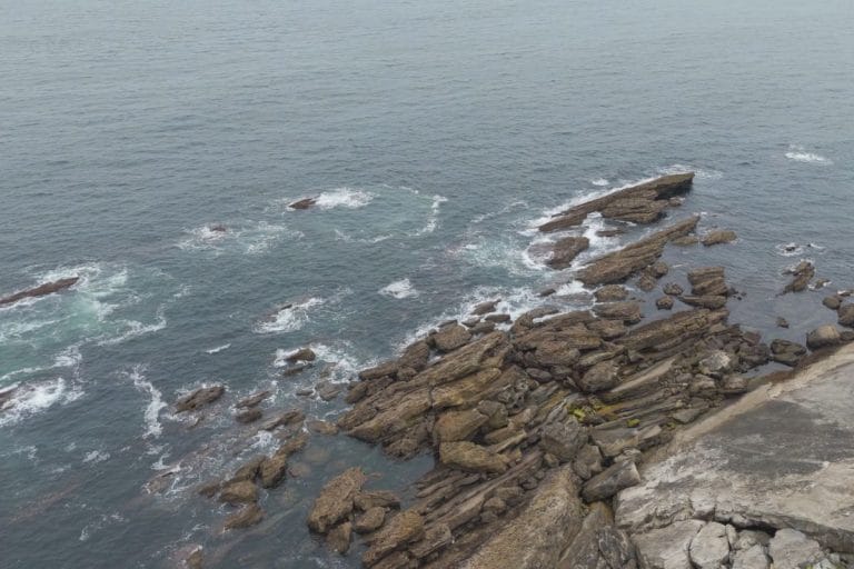Vista aérea del acantilado rocoso de Higer en Hondarribia, con el mar Cantábrico rompiendo sobre las formaciones de piedra.